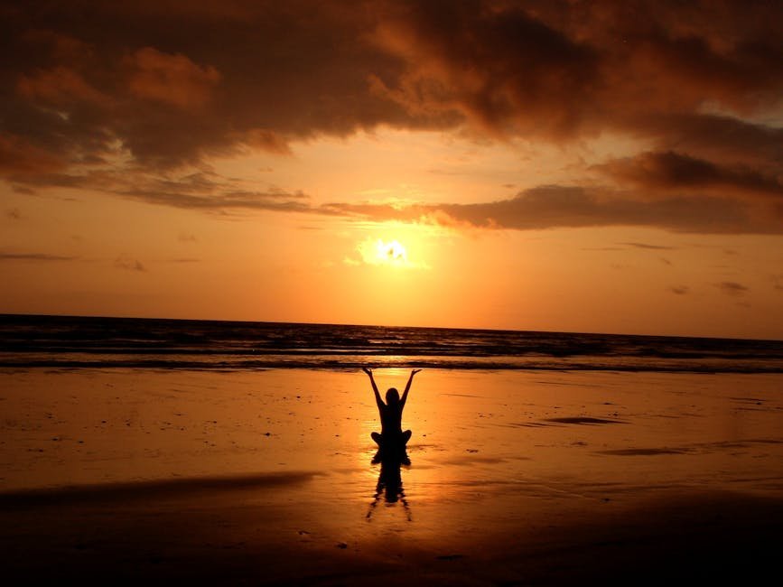 Peaceful meditation silhouette at sunset on a serene beach.